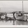 Spanish muskrat trapper standing beside his boat used to go out of the camp in the marshes and for fishing in other seasons. Delacroix Island, Louisiana. See general caption number one.