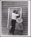Side strips are nailed over the wire sceen to hold the edges down tightly. A completed window screen. Screening demonstration. Charles County, La Plata, Maryland.