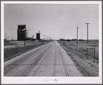 Grain storage elevators and highway through Lone Tree, North Dakota.