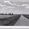 Highway, showing grain elevators and part of town of Froid, Montana.