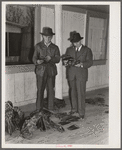 Manuel Malero, President of the Delacroix Island Corporation, and his nephew examining and grading muskrats at fur auction sale in dance hall. Delacroix Island, Louisiana.