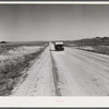 Passenger car and trailer enroute to California on highway across plains between Cheyenne and Laramie, Wyoming.