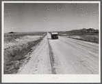 Passenger car and trailer enroute to California on highway across plains between Cheyenne and Laramie, Wyoming.