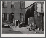 Negro slums. Alexander Court between K and L streets, N.W. Woman and her two children have lived in four small rooms eight and one half years and pay twelve fifty a month for rent ... Washington, D.C.
