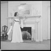 Unidentified woman in gown by fireplace