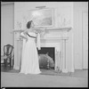 Unidentified woman in gown by fireplace