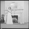 Unidentified woman in gown by fireplace