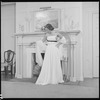 Unidentified woman in gown by fireplace