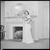 Unidentified woman in gown by fireplace