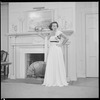 Unidentified woman in gown by fireplace