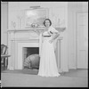 Unidentified woman in gown by fireplace
