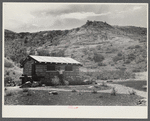 Man in front of his stone house.