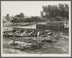 Foundation forms for homes under construction at the Resettlement Administration project, Ironwood, Michigan. Farm buildings in process of removal at left.