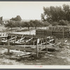 Foundation forms for homes under construction at the Resettlement Administration project, Ironwood, Michigan. Farm buildings in process of removal at left.
