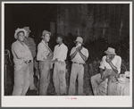 Group of migratory agricultural workers at grading station at Belcross, North Carolina, stop to wash and have their supper.