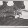 Migratory worker on the Norfolk-Cape Charles Ferry, writing a postcard home to his parents.