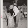 Migratory agricultural worker from Florida sewing potato sacks at a grading station at Belcross, North Carolina.