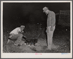 Mirgratory agricultural workers from the grading station at Belcross, North Carolina, cook their own supper of potatoes and salt pork.