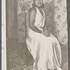 Teresa Roldan sits in long sleeveless dress