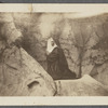 Nun kneeling amid rock formation, undated