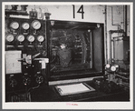 At the testing chamber for motors at the Pratt and Whitney Aircraft Corporation. After the engine is set up inside the chamber the door is sealed tight and the engine run at full blast for hours on end as an engineer watches it thru the window, records