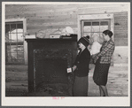 Mrs. Harvey and a neighbor watching her belongings being moved out of her house in the Camp Croft area near Whitestone, South Carolina.