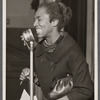 Claudia Jones at microphone smiling