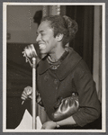 Claudia Jones at microphone smiling