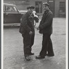 Two shipyard workers talking just outside the gates to the shipyard during lunch hour.