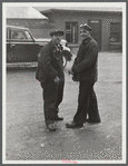 Two shipyard workers talking just outside the gates to the shipyard during lunch hour.