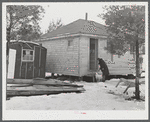 Mrs. Carol Porter setting out milk bottle. Shot shows small shack the Porters lived in while they were building their house.