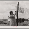 Mrs. Agnes Usher hanging clothes at her new prefabricated house at Hazlehurst Farms Inc. She had gone to Hinesville with her husband from Baxley, Georgia to work at Camp Stewart. When his work was over they moved to Hazlehurst Farms. Hazelhurst, Georgia.