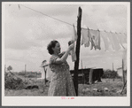 Mrs. Agnes Usher hanging clothes at her new prefabricated house at Hazlehurst Farms Inc. She had gone to Hinesville with her husband from Baxley, Georgia to work at Camp Stewart. When his work was over they moved to Hazlehurst Farms. Hazelhurst, Georgia.