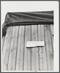 This sign was on a truck converted into living quarters at a camp for migratory workers near Fayetteville, North Carolina. It reads: "Will be back in week. Temporary lay off on acc. of material. Occupants".