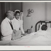 Chicago, Illinois. Provident Hospital. Doctor and a nurse attending a patient in the men's ward.