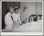 Chicago, Illinois. Provident Hospital. Doctor and a nurse attending a patient in the men's ward.