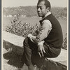 James Baldwin sitting on low wall by lake