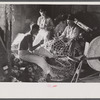 Fishermen in repair shack repairing nets and sharpening tools. The twine of these nets is impregnated with coal tar;