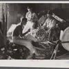 Fishermen in repair shack repairing nets and sharpening tools. The twine of these nets is impregnated with coal tar;