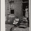 Negro family in front of their alley dwelling. The older woman is a cleaning woman in the U.S. government. Washington, D.C.