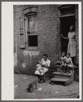 Negro family in front of their alley dwelling. The older woman is a cleaning woman in the U.S. government. Washington, D.C.