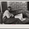 Negro reading in front of his alley dwelling home, Washington, D.C.