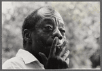 James Baldwin looking contemplative while smoking cigarette