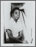 James Baldwin sitting with arms folded across torso