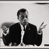 James Baldwin sitting at microphone