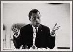 James Baldwin sitting at microphone