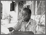 James Baldwin in checkered shirt marking pages