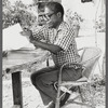 James Baldwin in eyeglasses and checkered shirt marking pages