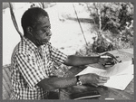 James Baldwin in checkered shirt marking pages