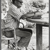 James Baldwin in eyeglasses and checkered shirt marking pages